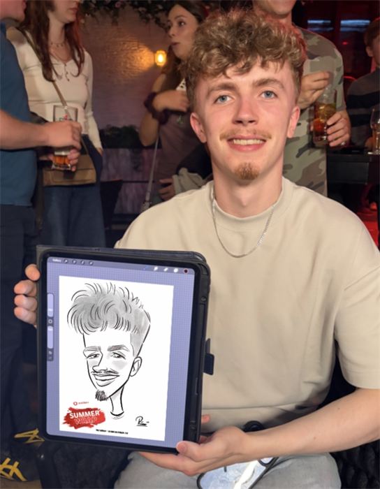 Young man with his live digital caricature at a summer party