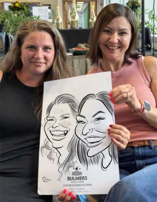 Two friends holding their hand-drawn paper caricature