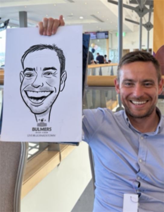 Guest holding up his hand-drawn paper caricature